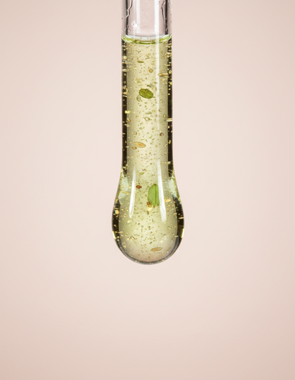 texture: macro goutte de sérum vert-doré au bout d'une pipette